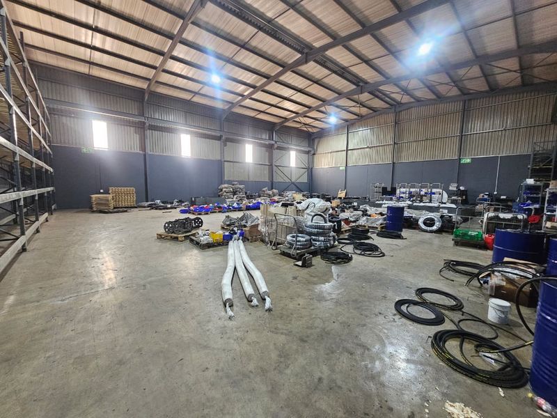 Spacious industrial warehouse featuring a steel portal frame, concrete flooring, high-bay lighting, and integrated racking systems suitable for storage or manufacturing operations.
