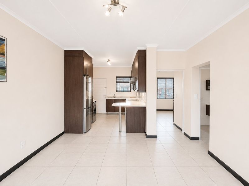 Spacious open-plan kitchen and living area featuring modern dark wood cabinetry, tiled flooring, and a functional breakfast bar layout.