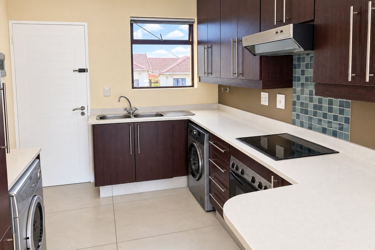 A modern kitchen featuring dark wood cabinetry, white stone countertops, integrated appliances, and tiled flooring, offering a clean and functional workspace.