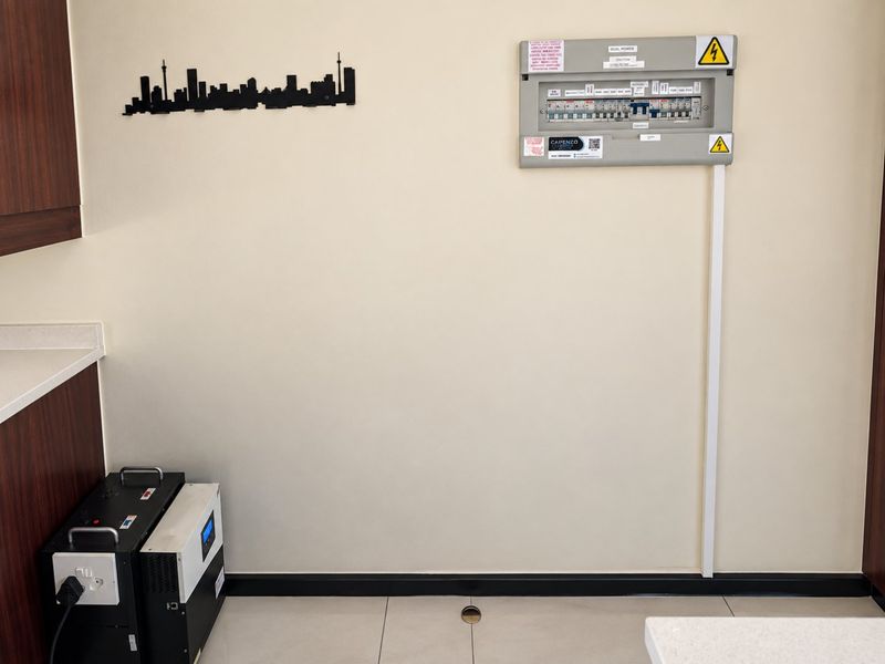Utility area featuring a wall-mounted electrical distribution board and a floor-standing inverter system.