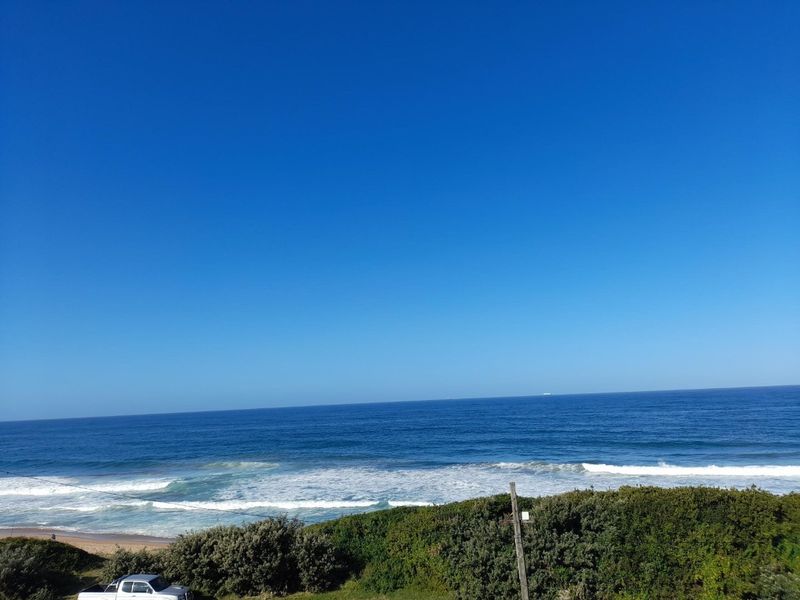A clear, expansive view of the ocean and coastline under a bright blue sky.