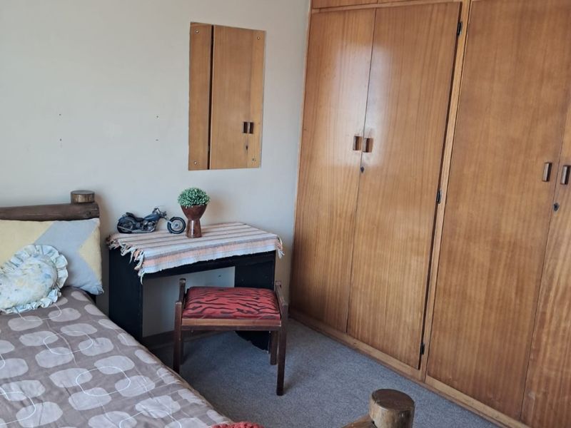 A bedroom featuring built-in wooden cupboards and carpeted flooring, offering functional storage space.