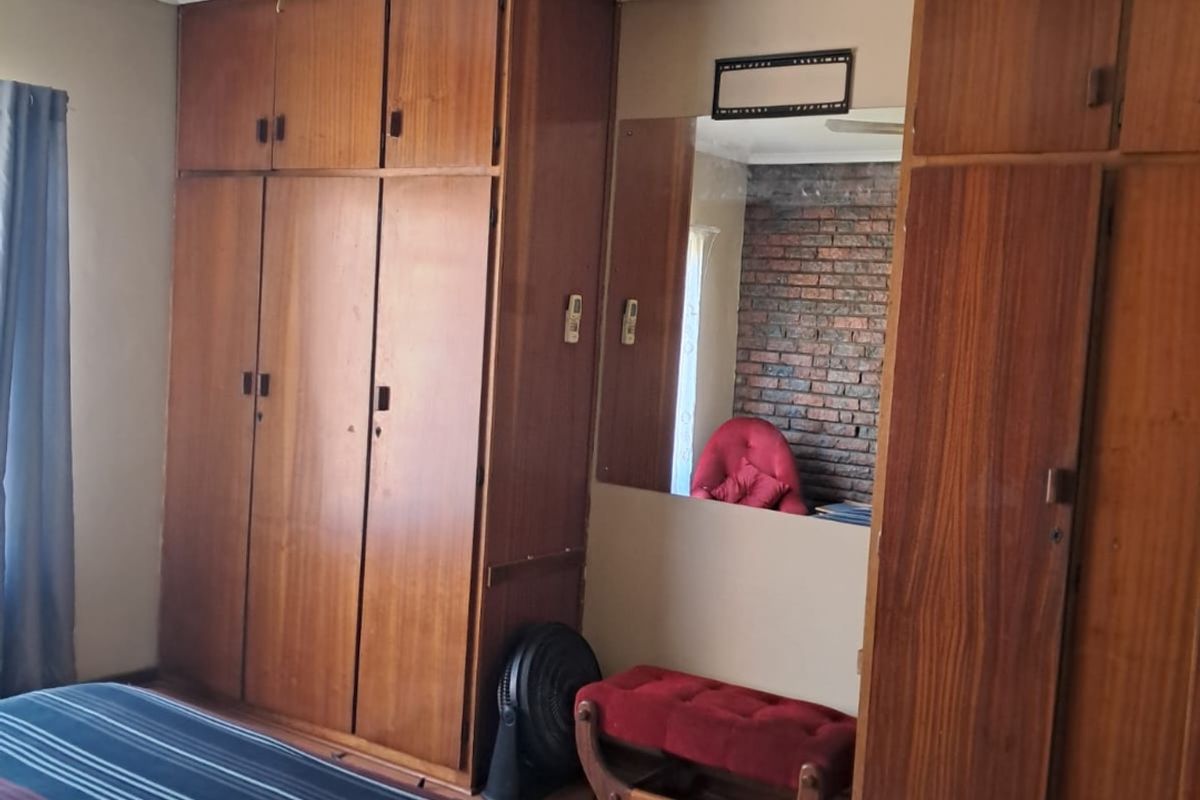 Bedroom featuring extensive built-in wooden cabinetry, laminate flooring, and a ceiling fan, offering ample storage space with a dated aesthetic.