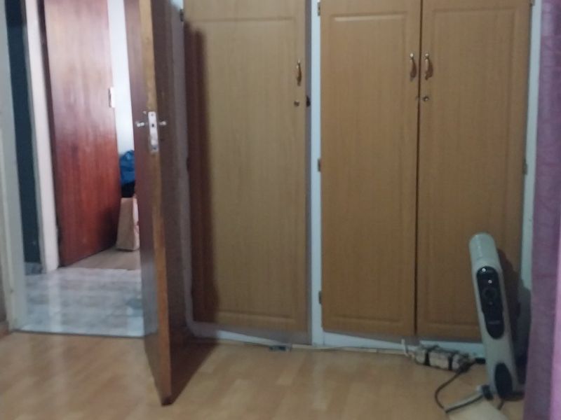 A bedroom featuring built-in cupboards and laminate flooring, with an open doorway leading to an adjacent room.