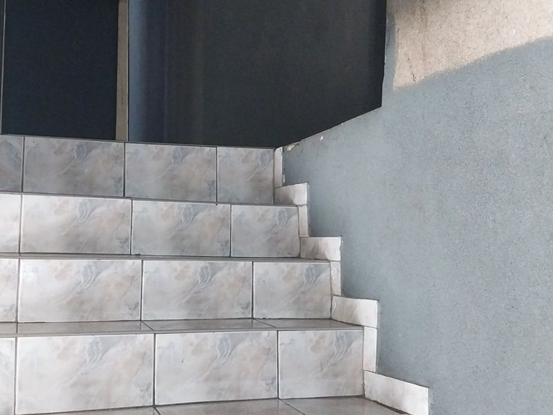 A staircase featuring tiled steps leading to an upper level, currently showing unfinished wall surfaces and paintwork requiring completion.