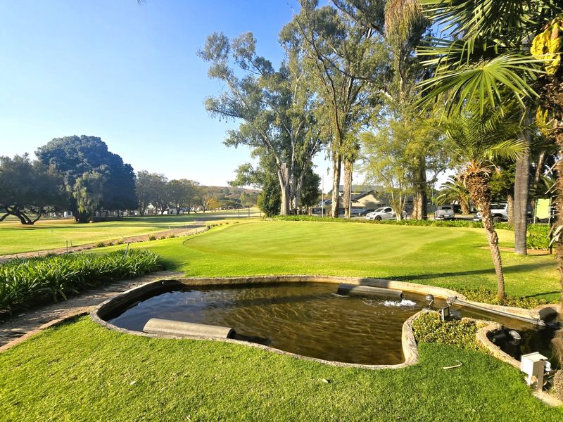 A scenic view overlooking a well-maintained golf course featuring a landscaped garden and a decorative pond.