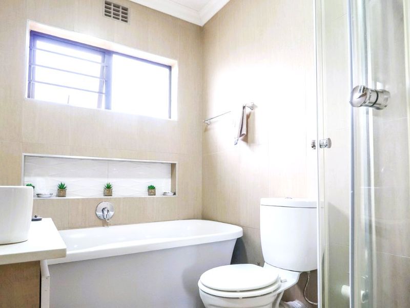 A modern bathroom featuring a freestanding bathtub, a glass-enclosed shower, a wall-mounted faucet, and a convenient recessed storage niche.