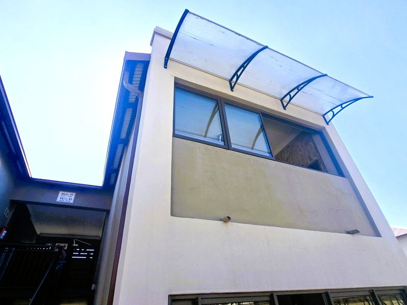 Exterior view of the apartment building featuring a modern polycarbonate window awning and aluminium window frames.