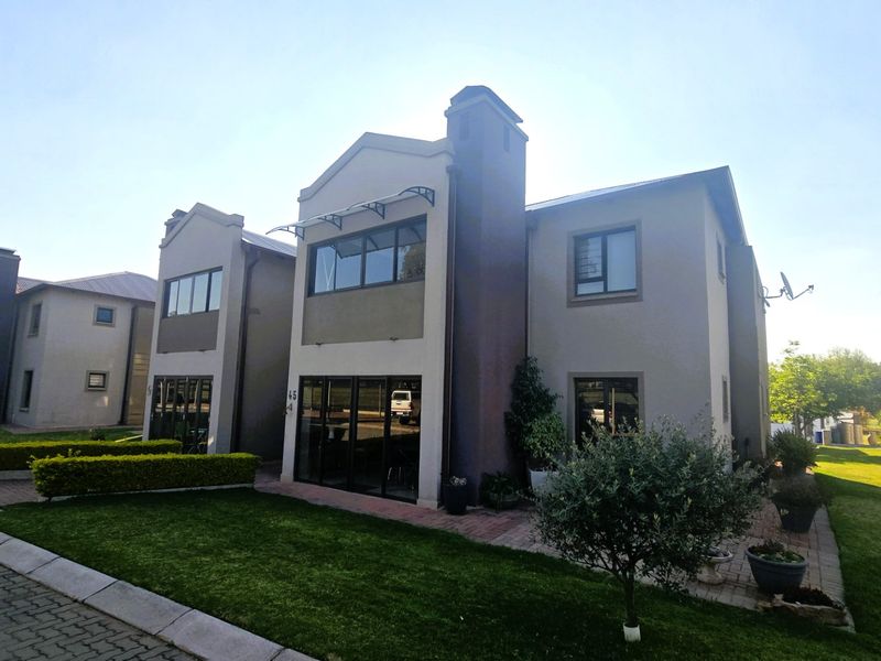 Rear view of a modern apartment building featuring a paved patio area, well-maintained lawn, and large sliding glass doors.
