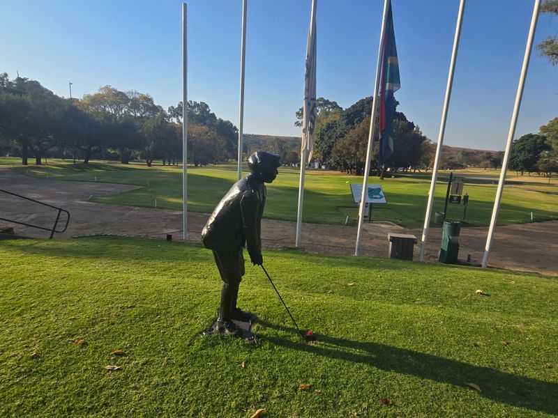 A scenic view overlooking a well-maintained golf course with landscaped lawns, paved pathways, and flagpoles.