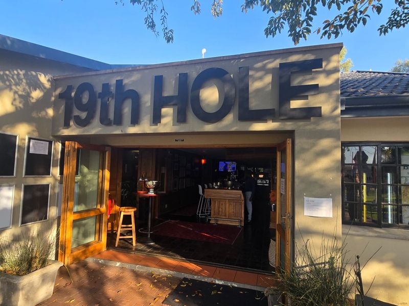 Exterior view of the 19th Hole clubhouse entrance featuring wooden double doors and classic architectural detailing.