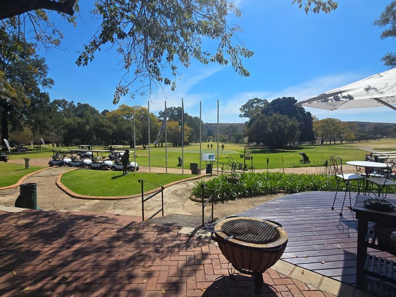 A scenic outdoor view overlooking a golf course, featuring a combination of brick paving and timber decking in a landscaped setting.