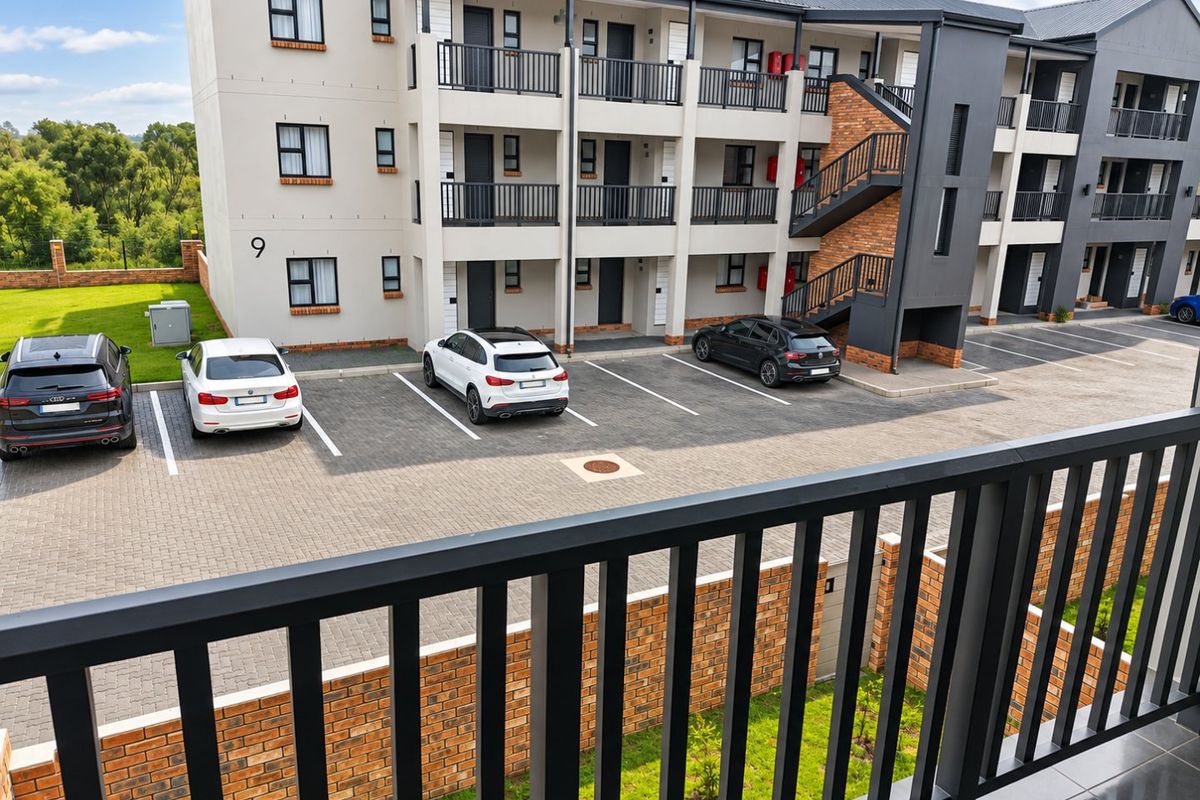 View of the apartment complex exterior featuring a paved parking area, external staircases, and balcony access.