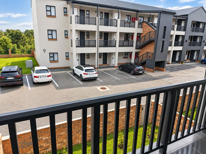 View of the apartment complex exterior featuring a paved parking area, external staircases, and balcony access.