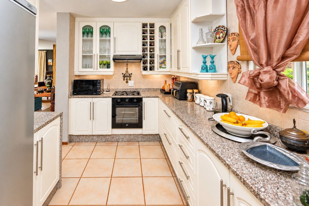 A well-maintained kitchen featuring white cabinetry, granite countertops, a gas hob, and an integrated oven, offering a functional and classic cooking space.