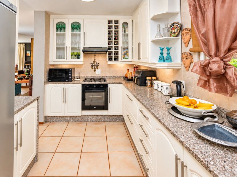 A well-maintained kitchen featuring white cabinetry, granite countertops, a gas hob, and an integrated oven, offering a functional and classic cooking space.