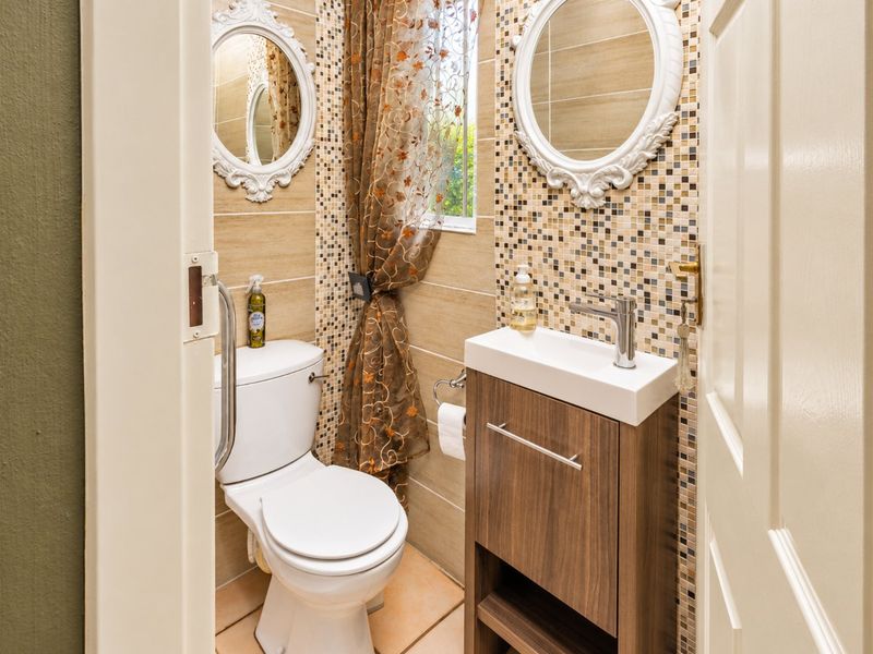 Compact guest bathroom featuring a modern vanity, mosaic tile accents, and a wall-mounted grab rail for accessibility.