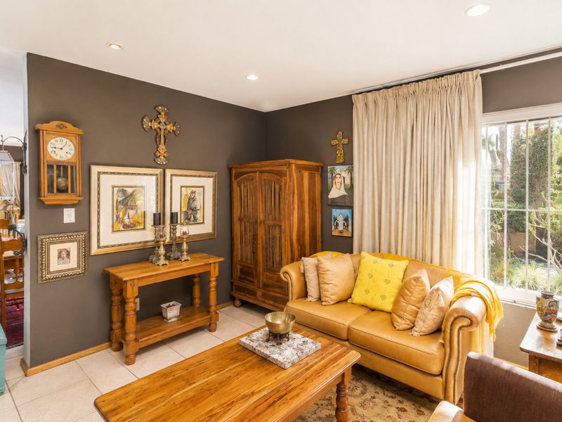 A cozy living room featuring dark painted walls, tiled flooring, and recessed downlighting, with a large window providing natural light.