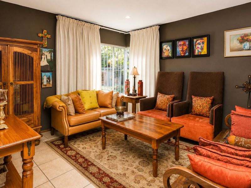 A cozy living room featuring tiled flooring, recessed lighting, and a window with security bars, finished with dark wall paint.