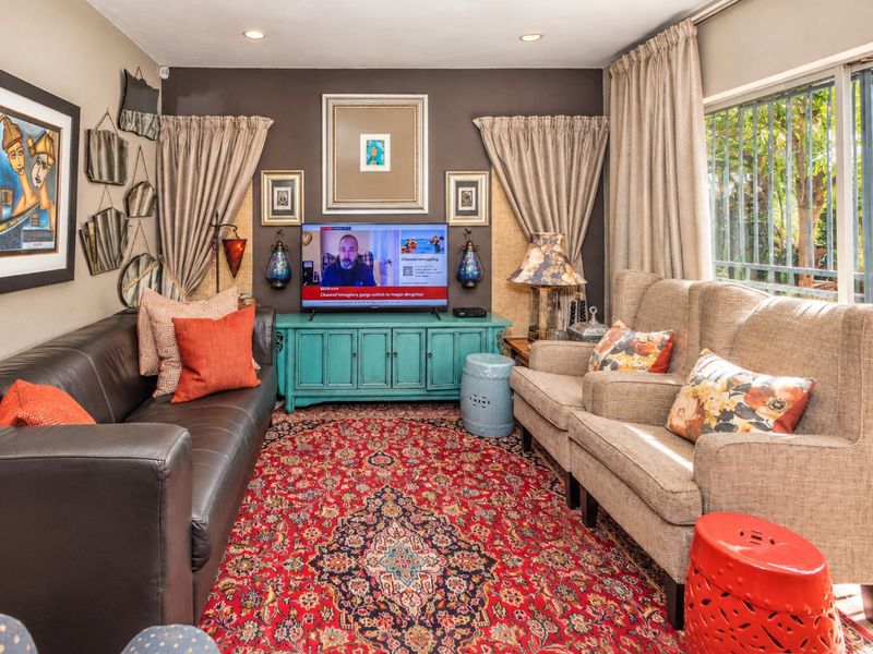 A cozy living room featuring recessed lighting and a large window with security bars, providing natural light and a view of the garden.