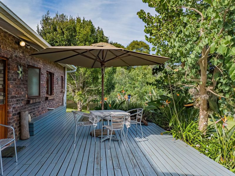 A spacious outdoor timber deck featuring a brick facade, providing a pleasant area for relaxation overlooking the surrounding garden.