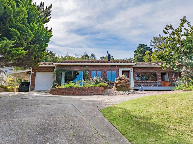 Front elevation of a single-story brick house featuring a concrete driveway, attached garage, carport, and established garden landscaping.