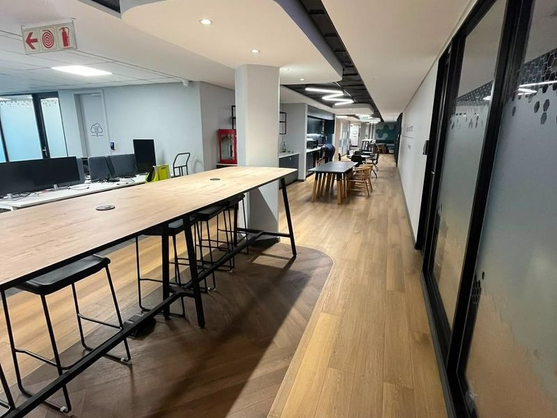 Modern open-plan office space featuring high-quality herringbone wood flooring, contemporary suspended ceiling design, and glass partition walls providing a professional work environment.