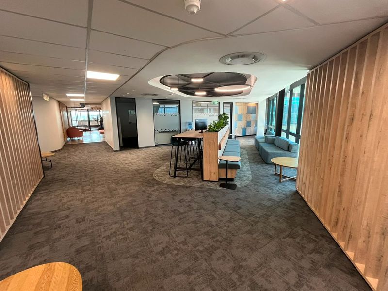 Modern open-plan office space featuring contemporary timber slat wall paneling, suspended ceilings with recessed lighting, and high-quality carpet flooring.