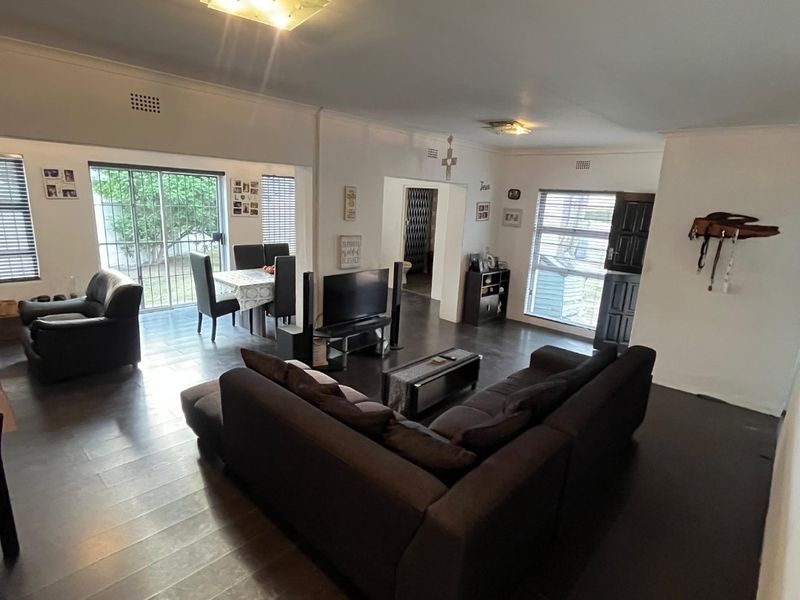 Spacious open-plan living and dining area featuring dark laminate flooring and large sliding glass doors providing access to the outdoor space.