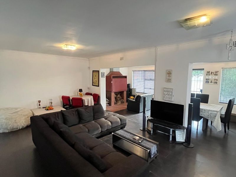 Spacious open-plan living and dining area featuring dark laminate flooring, a built-in fireplace, and neutral wall finishes.