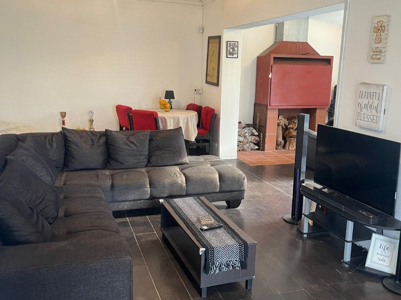 Open plan living area featuring dark tiled flooring and a prominent built-in fireplace in the adjacent space.