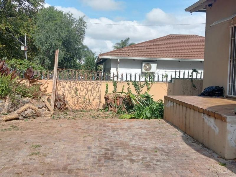 Rear exterior area featuring a paved patio, perimeter wall with security features, and access to the main dwelling via a sliding door.