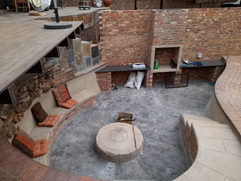 Sunken outdoor entertainment area featuring a built-in braai, brick masonry, and integrated concrete seating, ideal for social gatherings.