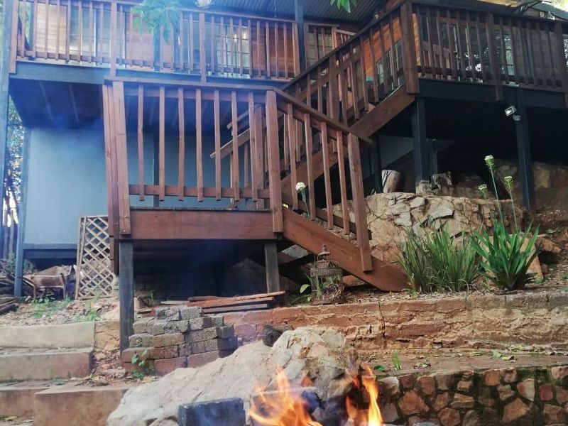 Rear view of a multi-level timber deck with staircase, overlooking a natural garden area featuring a stone fire pit and retaining walls.