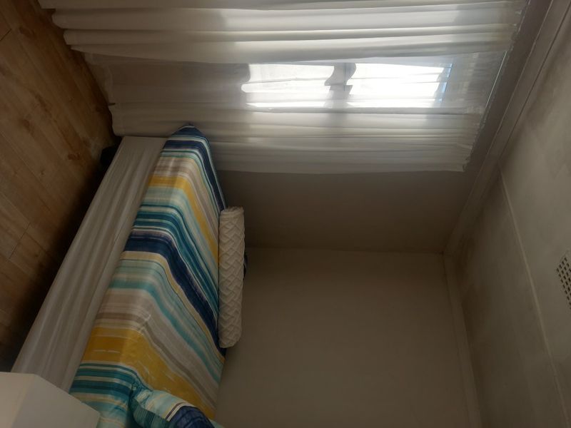 A bedroom featuring laminate flooring and a ceiling vent, showing signs of wall and ceiling discoloration requiring maintenance.