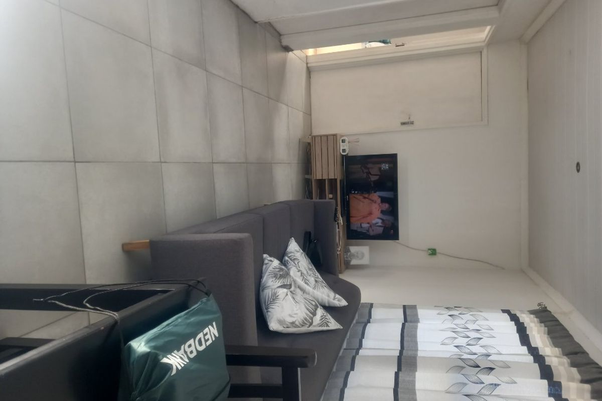 A living room area featuring large format floor tiles and a standard internal door.