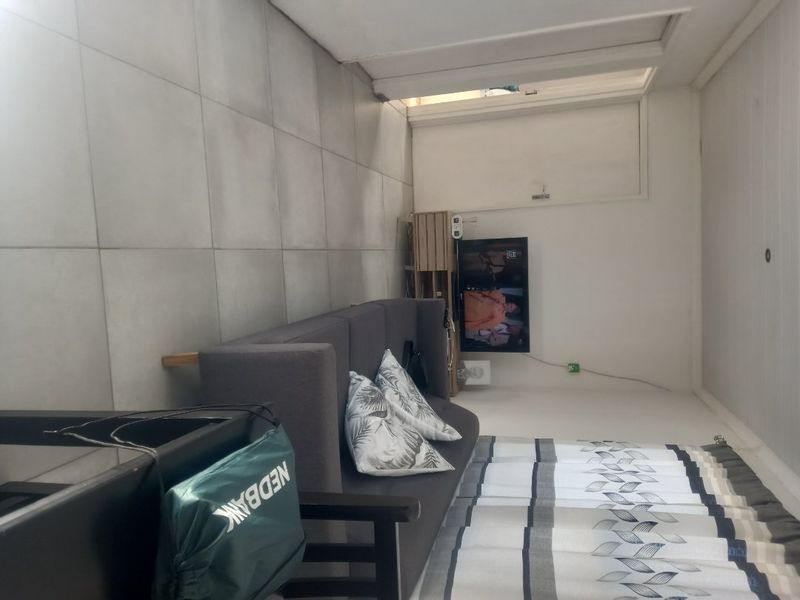 A living room area featuring large format floor tiles and a standard internal door.