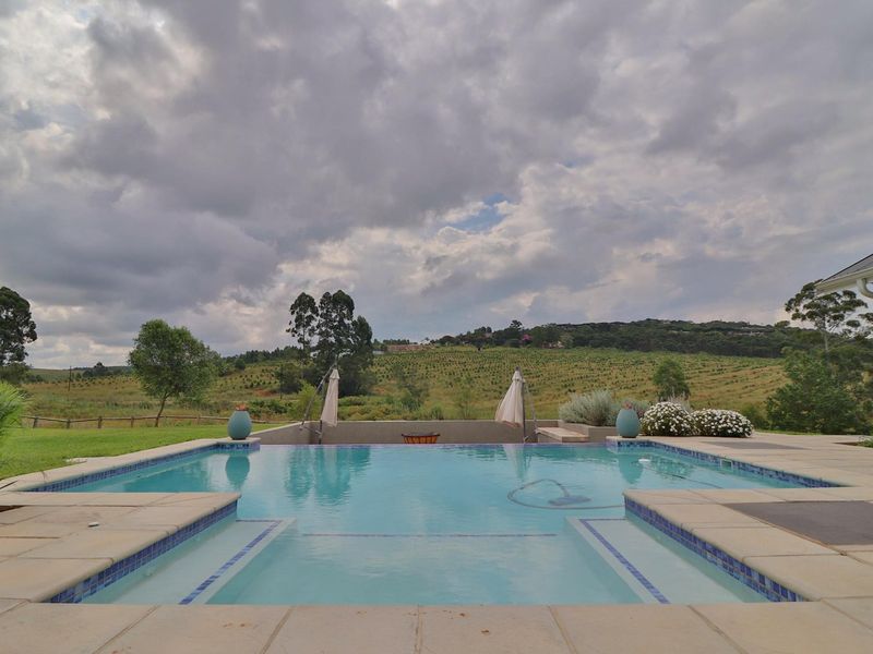 A well-maintained swimming pool with tiled surround, featuring a scenic view of the surrounding landscape.