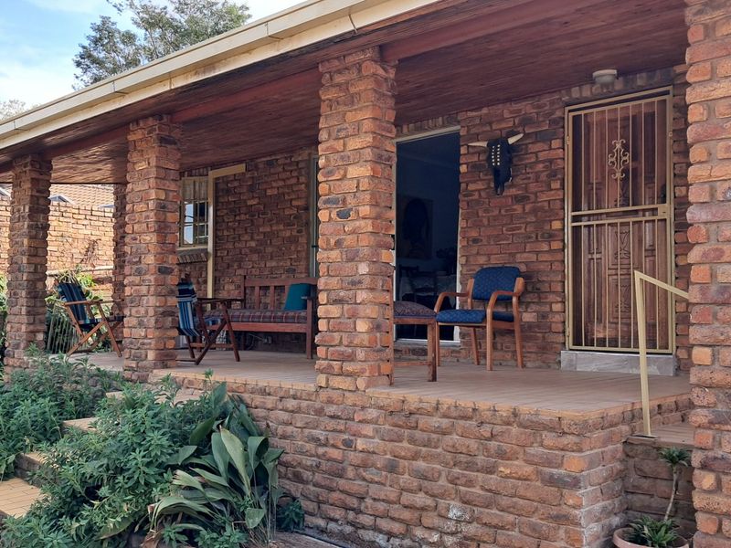 A covered patio area featuring exposed brick columns, a timber ceiling, and tiled flooring, providing a rustic outdoor space for relaxation.