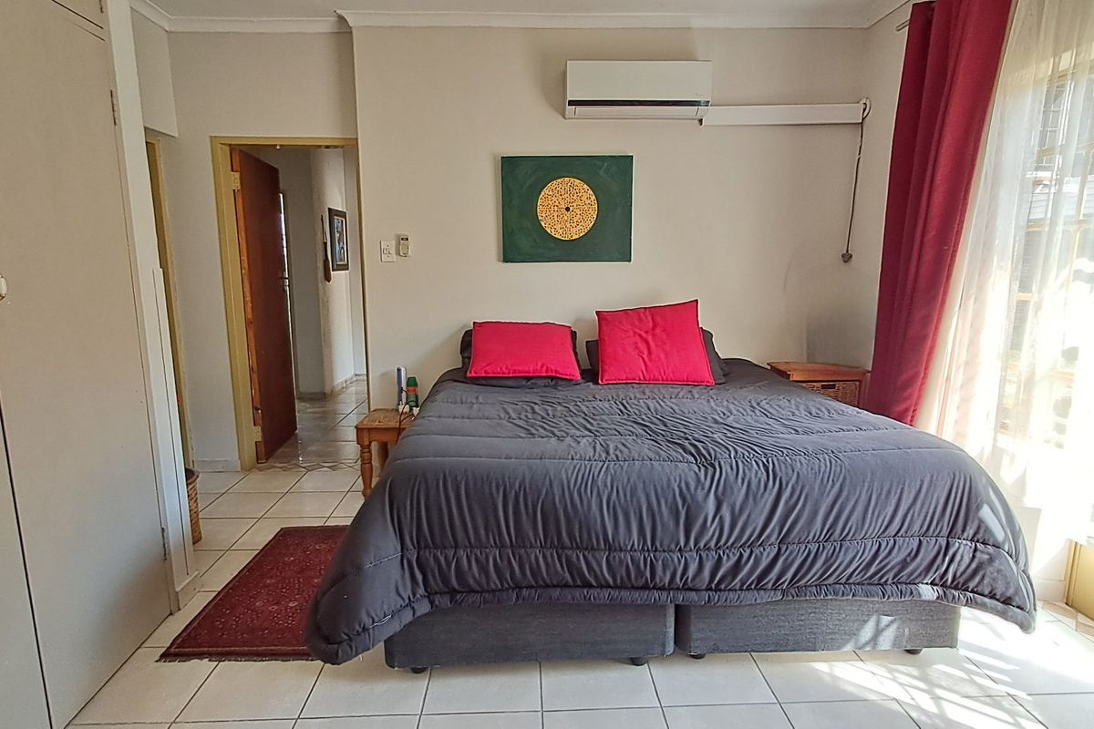 A bedroom featuring tiled flooring, a built-in wardrobe, and a wall-mounted split-system air conditioning unit.