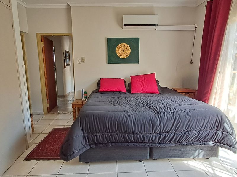 A bedroom featuring tiled flooring, a built-in wardrobe, and a wall-mounted split-system air conditioning unit.