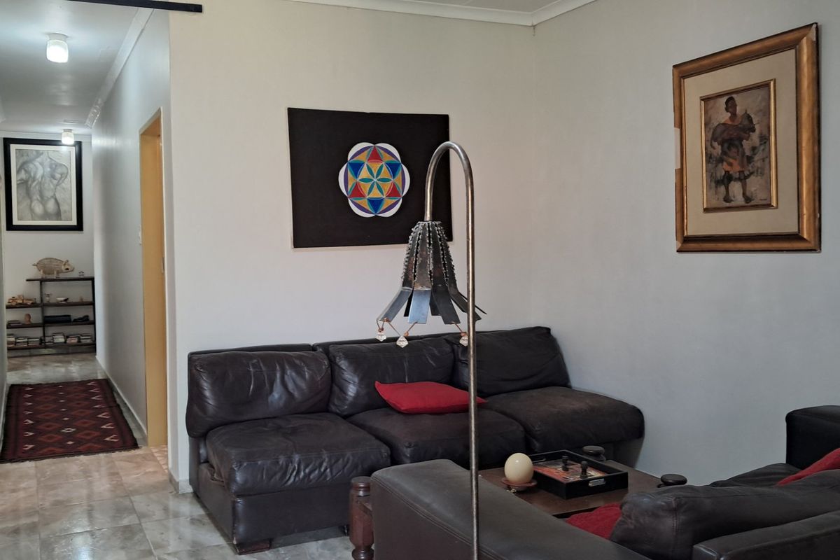 A comfortable living room area featuring tiled flooring and neutral wall finishes, leading into a connecting hallway.