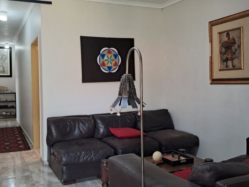 A comfortable living room area featuring tiled flooring and neutral wall finishes, leading into a connecting hallway.