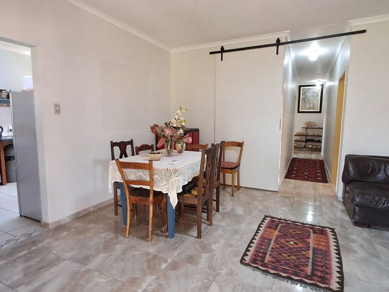 Open plan living and dining area featuring tiled floors, a sliding barn door, and an adjacent kitchen with built-in appliances.