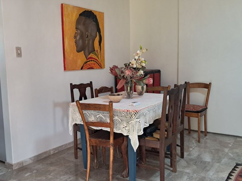 A dining area featuring tiled flooring, adjacent to a kitchen space with built-in cabinetry.