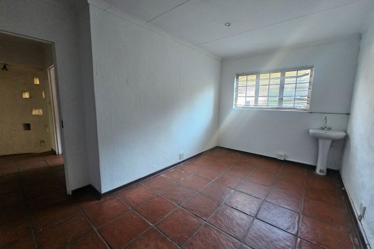 An empty bedroom featuring terracotta tiled flooring, a built-in pedestal basin, and venetian blinds, offering a blank canvas for renovation.