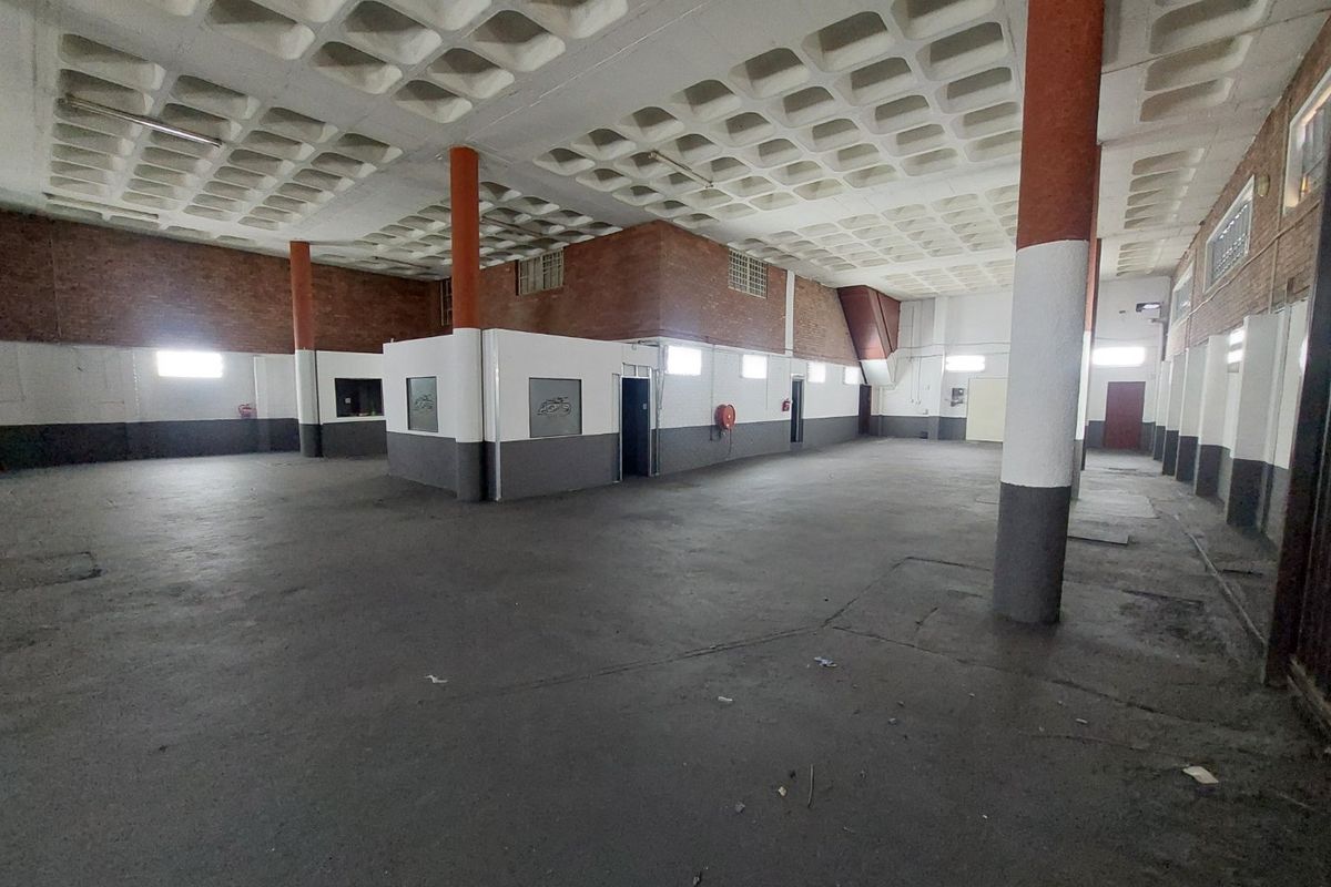 Spacious open-plan commercial area featuring a distinctive waffle slab ceiling, exposed brick walls, and durable concrete flooring, suitable for various business applications.