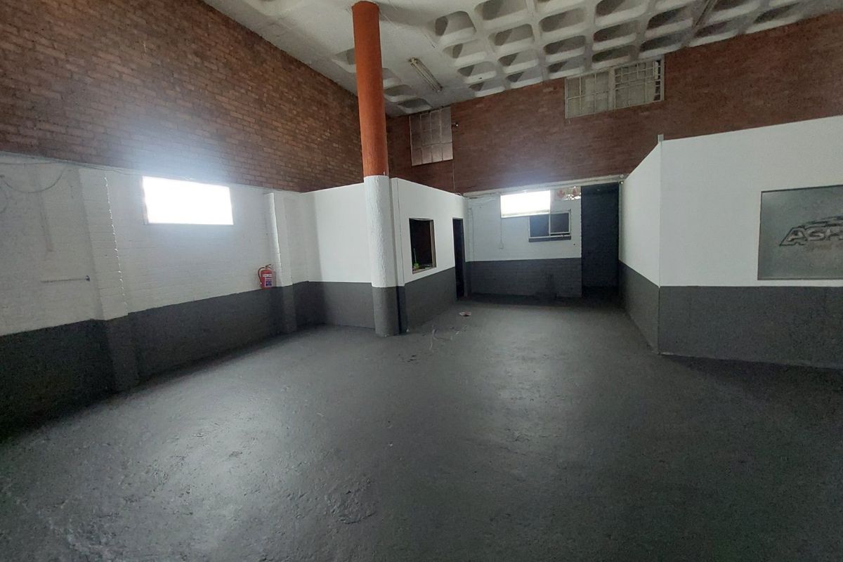 An open-plan commercial utility space featuring exposed brickwork, a waffle slab ceiling, and painted concrete flooring.