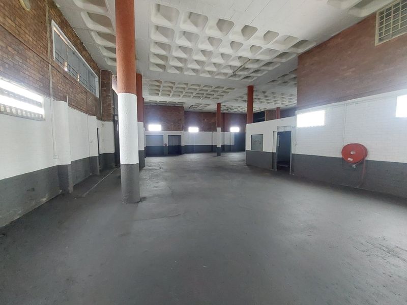 Spacious open-plan commercial warehouse area featuring a distinctive waffle slab ceiling, structural columns, and exposed brickwork, suitable for various industrial or retail applications.