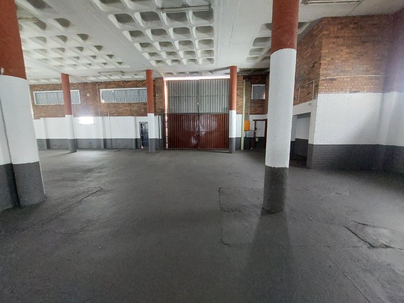 Spacious industrial utility area featuring high waffle slab ceilings, exposed brickwork, concrete flooring, and large industrial access doors.